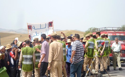 المشاركون في المسيرة حاملين للاعلام الوطنية وصور جلالة الملك ولافتات يتعرضون للحصار